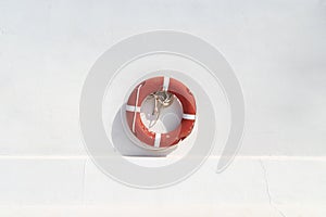 Red swimming pool lifebuoy on the white wall background. Minimalistic wallpaper