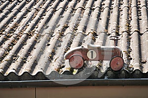 An red swing car placed on an old gray corrugate fibre cement roof covered with moss. photo