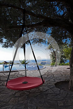 Red swing in the garden under a tree