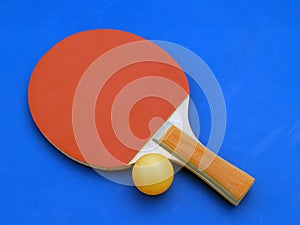 red table tennis ping pong racket with orange plastic ball on blue court