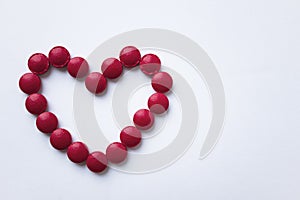 The red tablets are arranged in the shape of a heart. Red heart pills. The concept of a healthy heart.