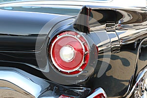 Red tail light on a classic black car.