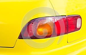 Red taillight on yellow car. Backlight of modern sport car. Four wheels transport.