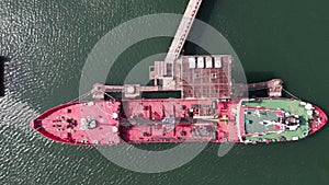 Red tanker ship loading and unloading oil and gas storage at industrial dock port