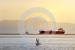 A red tanker ship sailing at high seas in the Bering sea at sunset