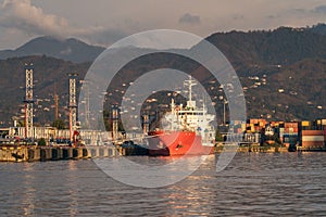 Red tanker ship at terminal port. Transportation, logistics and unloading of gas or oil in industrial harbor