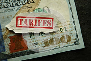 Red tariffs stamp on a US hundred dollar bill