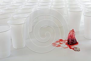 Red teabag beset by a group of white plastic cups, abstract conc