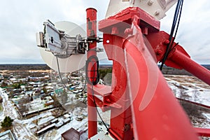 Red telecommunication tower with antenna and installed radio microwave equipment with coaxial cabel for transmitting data to other