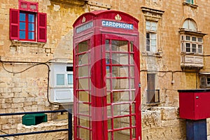 A red telephone booth on the background of an old residential building