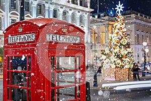 A red telephone booth in front of an illuminated Christmas Tree in Central London, UK