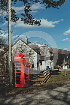 Red telephone box on a side of a road in the countryside in the UK