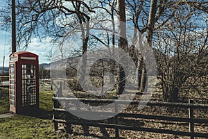 Red telephone box on a side of a road in the countryside in the UK