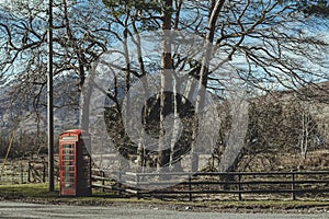 Red telephone box on a side of a road in the countryside in the UK