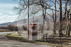 Red telephone box on a side of a road in the countryside in the UK