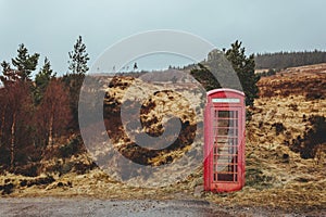 Red telephone box on a side of a road in the Scottish Highlands