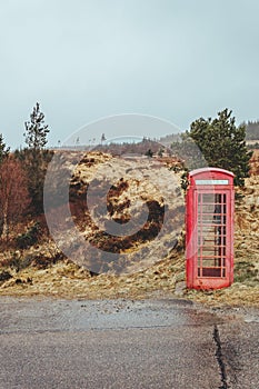 Red telephone box on a side of a road in the Scottish Highlands