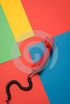 Red telephone handset with curly cord on bright background