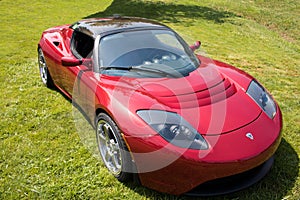 Red Tesla Roadster Sports Car Front Side in Green Field