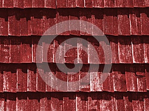 Red texture of wooden tile roof. Shingle aged wooden Background. Backdrop with small overlapping colored wooden shingles on roof