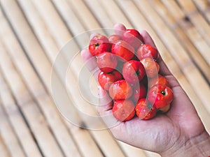 Red thai cherry in left hand bamboo wood pattern and background