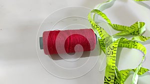 red thread and green measuring tape tools for sewing