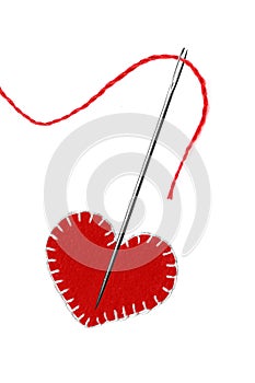 Red thread, needle and heart isolated on white