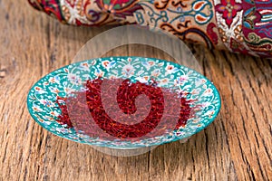 Red Threads And Yellow Style High Grade And Strength Of Dry Saffron Spice On Persian Turquoise Handmade Design Plate On Wooden Ta