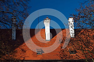 Red tile roof with chimney on blue sky background