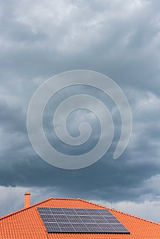 Red tile roof with photovoltaic panels during stormy weather Solar PV installation and dark blue sky