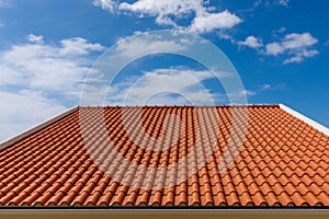 Red tiles panels roof under blue sky.