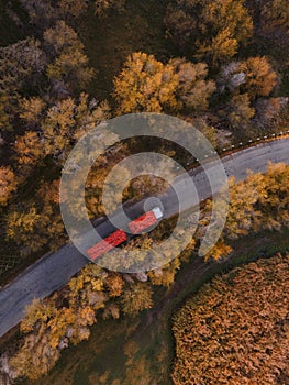 Red tipper truck on street road highway transportation. Semi-truck autumn countryside aerial view photo