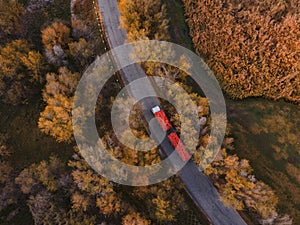 Red tipper truck on street road highway transportation. Semi-truck autumn countryside aerial view