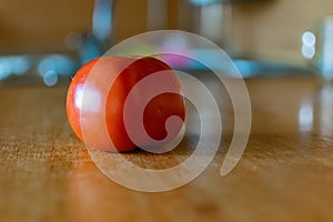 Red tomato on a brown wooden table. A round vegetable is placed singly in the kitchen