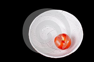 Red tomato on the ceramic bowl prepared for salad