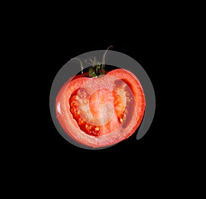 The red tomato cut half-and-half on a black background.