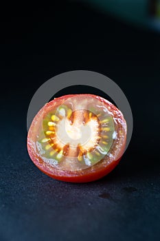 The red tomato cut half-and-half on a black background