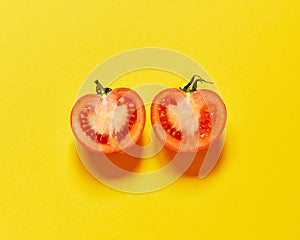 Red tomato cut in half isolated in yellow background viewed from above