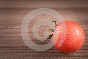 Red tomato with drops of water on wooden bckground
