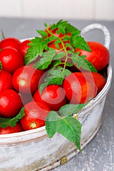 Red tomato in grey basket on grey background. Harvest. Full box of tomatoes. Close up.