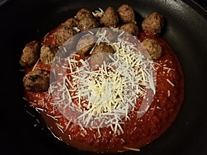 Red tomato pasta sauce and meatballs with cheese in skillet or pan