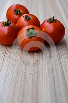 Red tomato on plain wooden table, essential vegetables for all essential foods, view of unpeeled vegetables with plain background