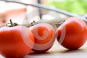 Red tomato on plain wooden table, essential vegetables for all essential foods, view of unpeeled vegetables with plain background