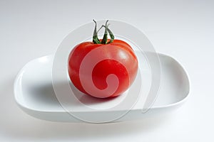 Red tomato on white plate