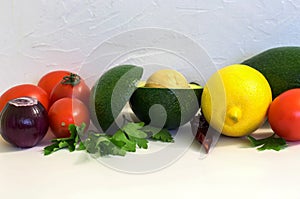 Red tomatoes and green avocado with lemon on white background, guacamole