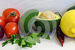 Red tomatoes and green avocado with lemon on white background, guacamole