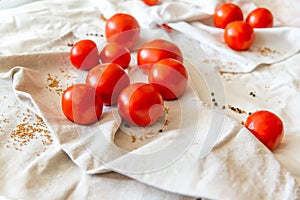 Red tomatoes on a linen towel. In the folds of the fabric of the moaning pepper and mustard in the grains.