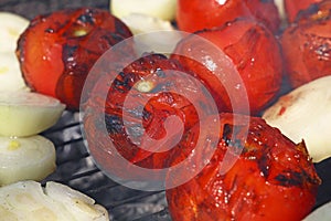 Red tomatoes and onions on bbq grill close up