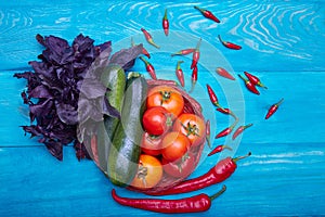 Red tomatoes with peppers, basil and zucchini on a wooden background. Ketchup sauce ingredients. Colorful vegetables.