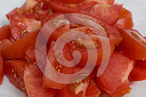 Red tomatoes sliced for salad on a white plate